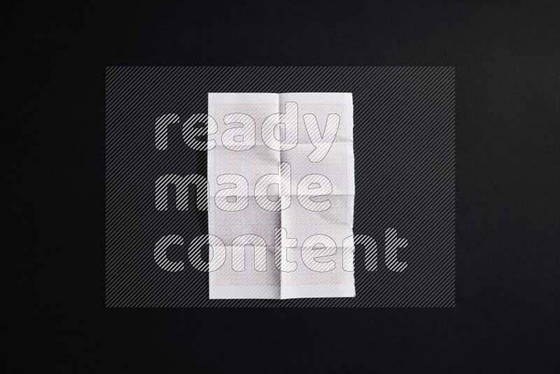 Folded notebook sheet on black background