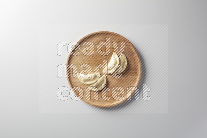 Four Sambosas on a wooden round plate on a white background