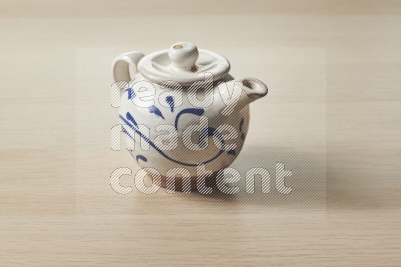 A pottery teapot on light wooden background