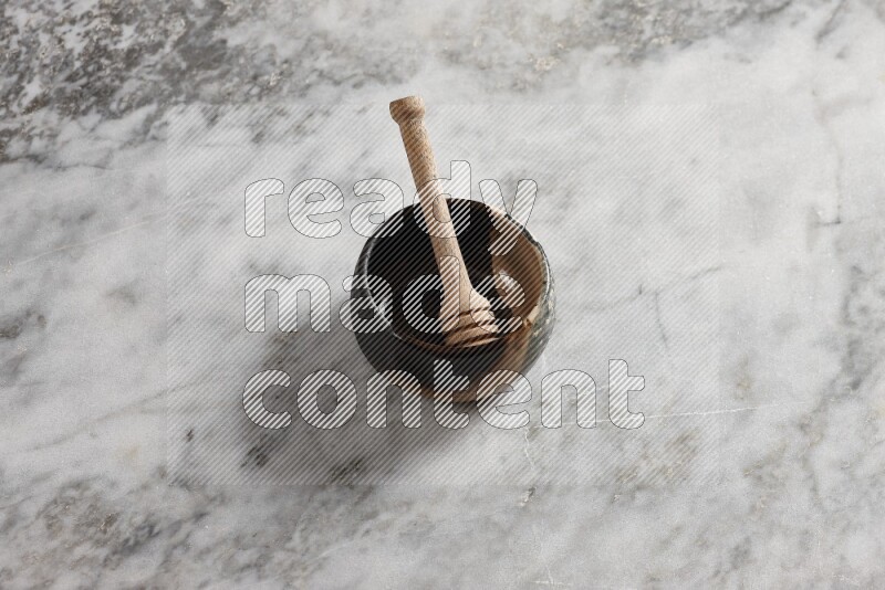 Multicolored pottery bowl with wooden honey dipper in it on grey marble background
