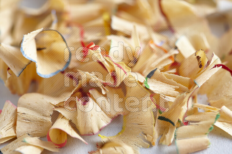 A close-up showing a small pile of pencil shavings with varied color edges on grey background