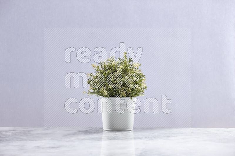 Artificial plant in white pot on grey marble background