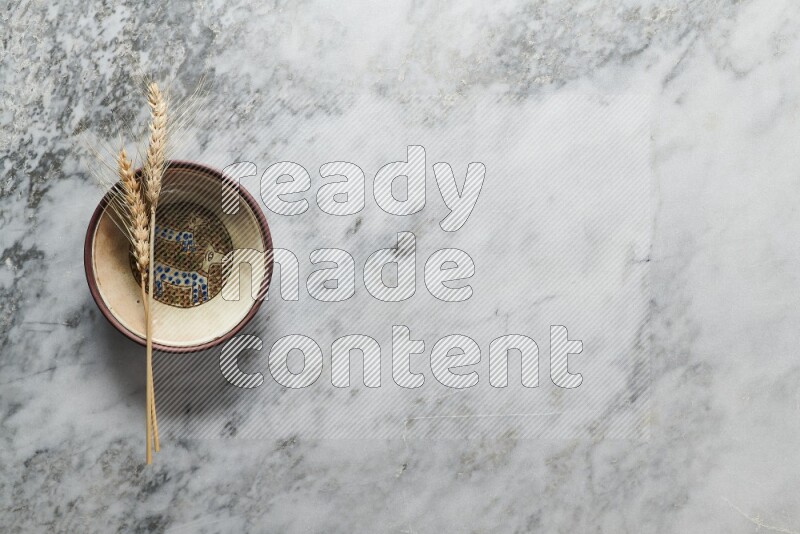 Wheat stalks on decorative pottery plate on grey marble background