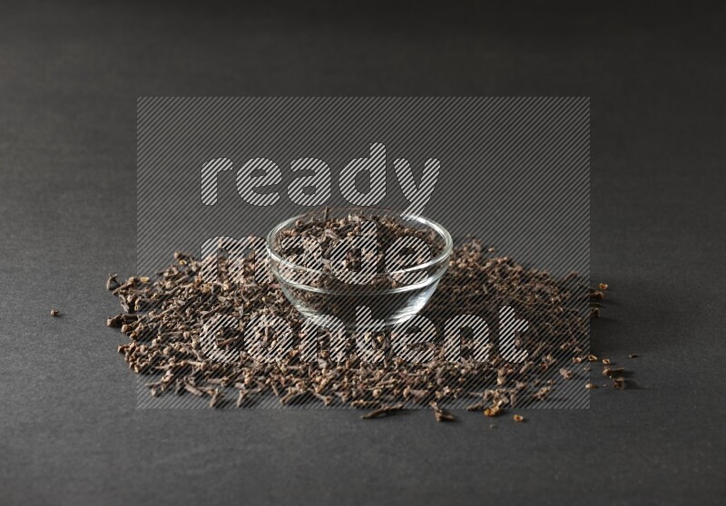 A glass bowl full of cloves on a black flooring