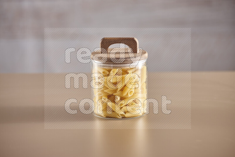 Raw pasta in glass jars on beige background