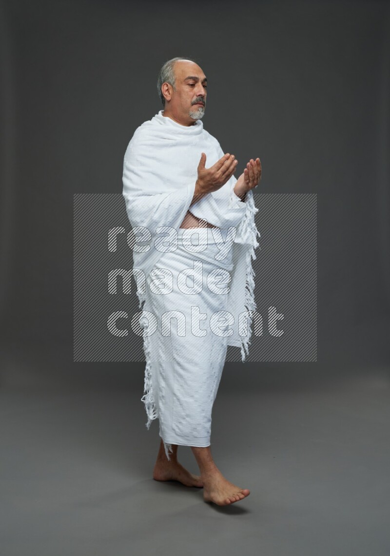 A man wearing Ehram Standing dua'a on gray background