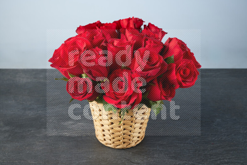 Vibrant red roses in a wicker basket on black marble background