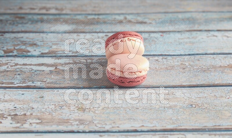 45º Shot of two Pink Litchi Raspberry macarons on light blue wooden background