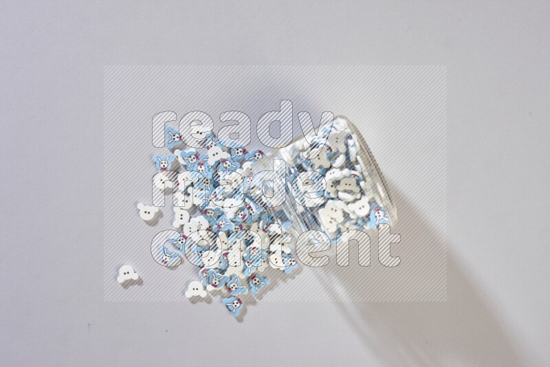 Colored buttons in a glass jar on grey background