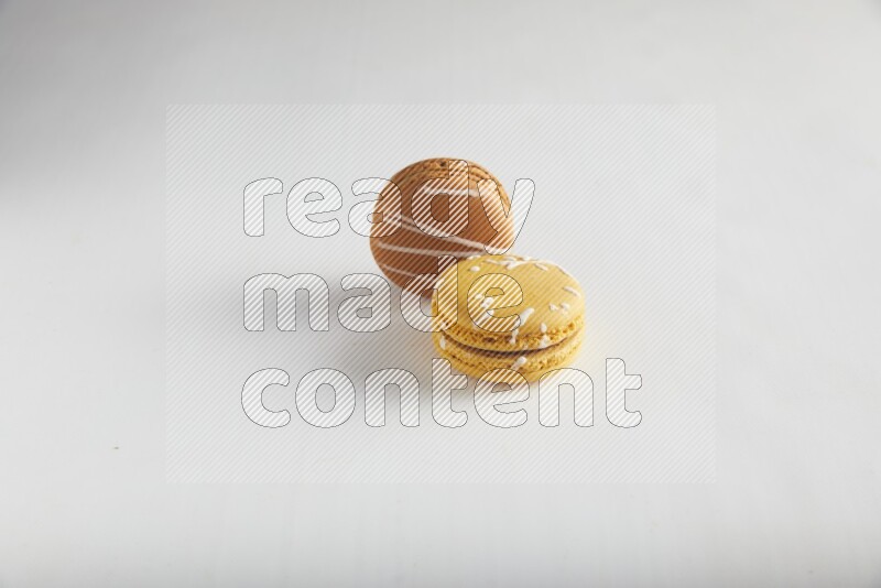 45º Shot of of two assorted Brown Irish Cream, and Yellow Piña Colada macarons on white background