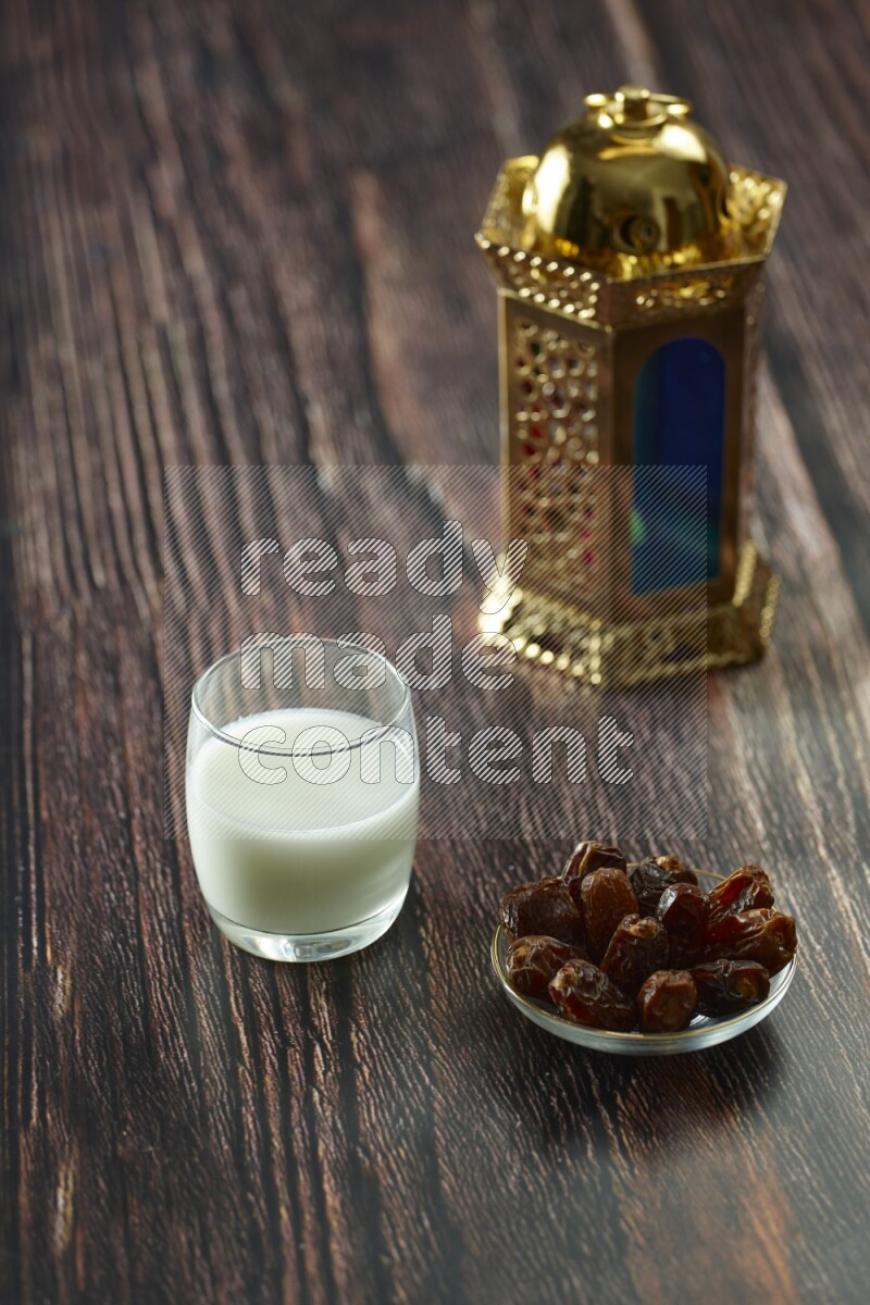 A golden lantern with different drinks, dates, nuts, prayer beads and quran on brown wooden background
