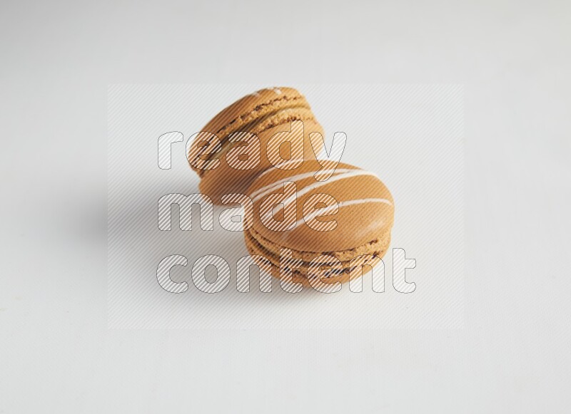 45º Shot of two Brown Irish Cream macarons on white background