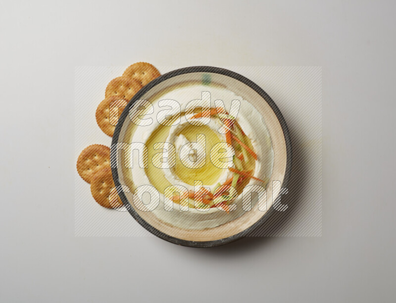 Lebnah garnished with sliced carrots &cucumber in a pottery plate on a white background