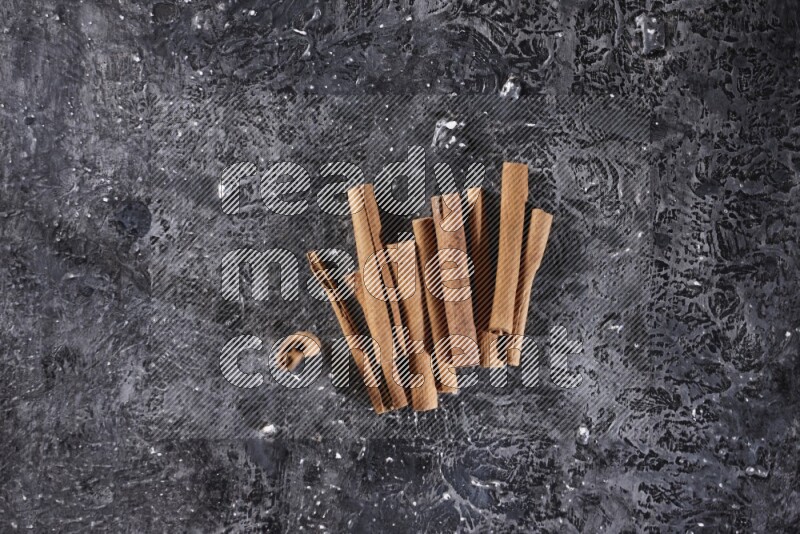 Cinnamon sticks on a textured black background