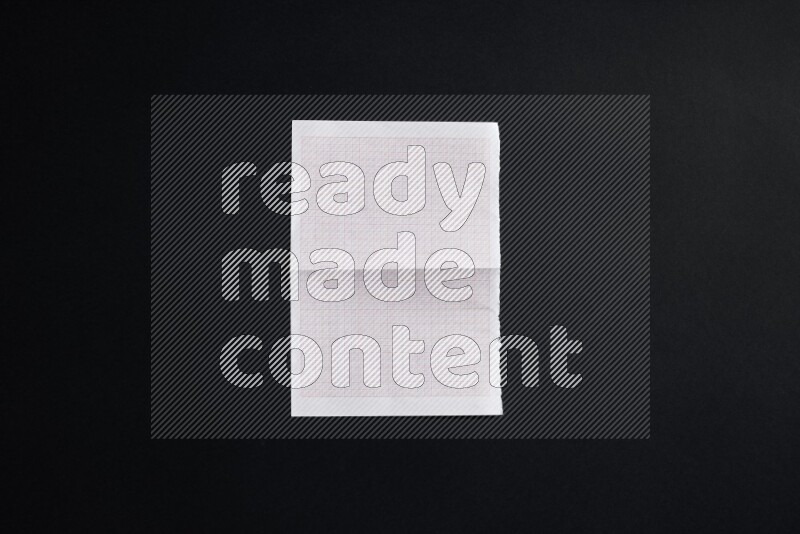 Folded notebook sheet on black background