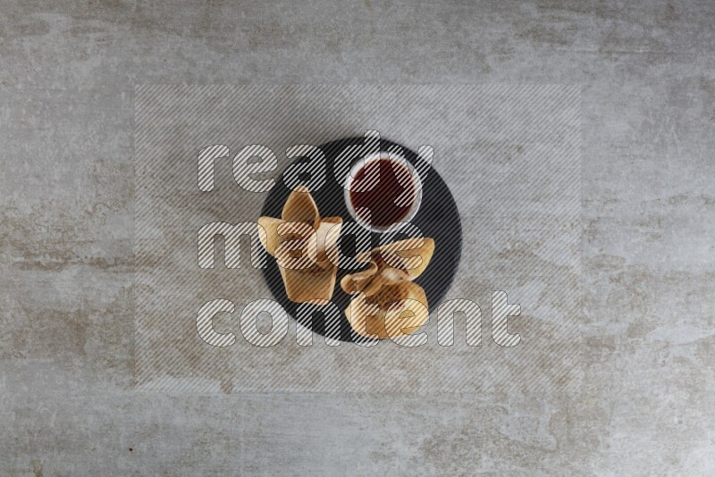wonton cups with soy sauce ramkin on circle slate on grey textured counter top