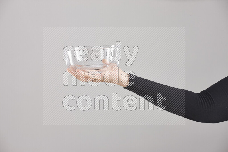 A woman in black abaya holding different glassware in different positions
