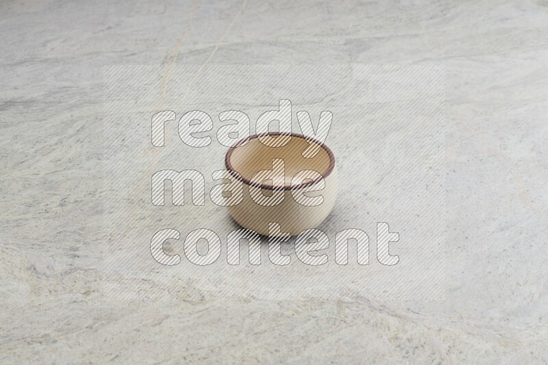 A beige pottery oven bowl on grey marble background