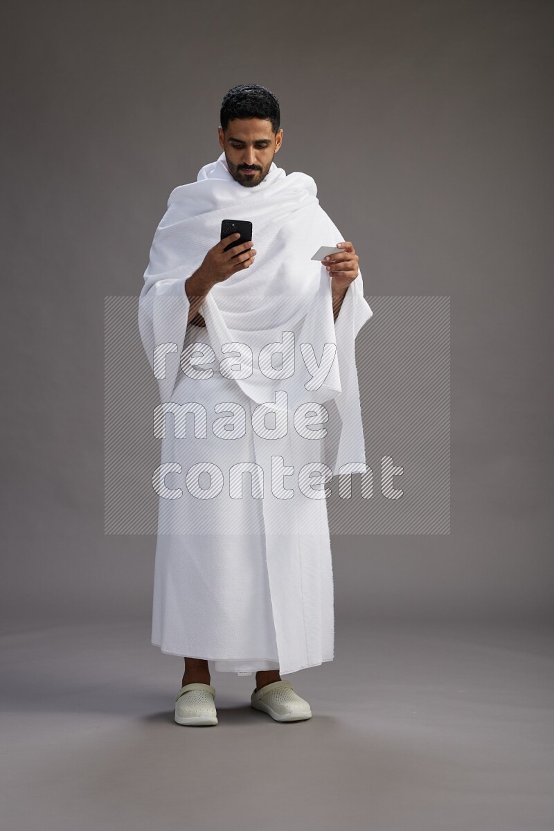 A man wearing Ehram Standing holding ATM card on gray background