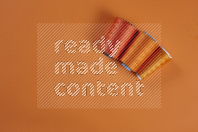 An orange collection of sewing and tailoring tools arranged on a orange background