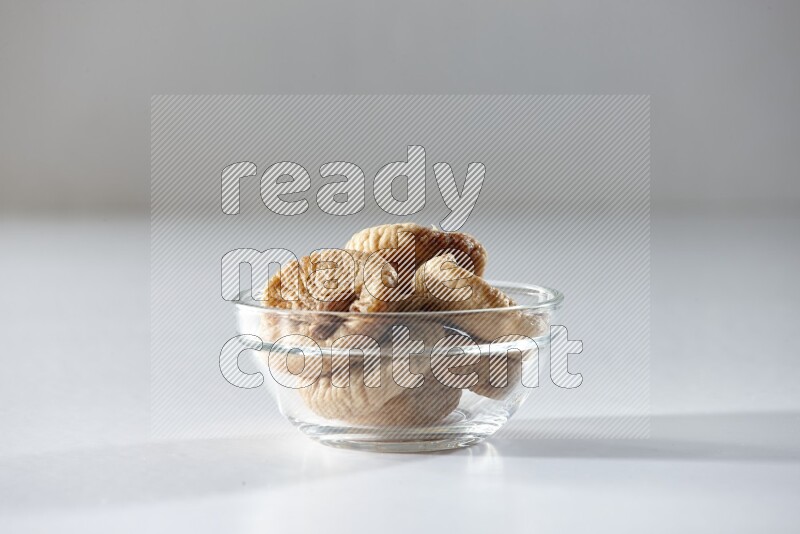 A glass bowl full of dried figs on a white background in different angles