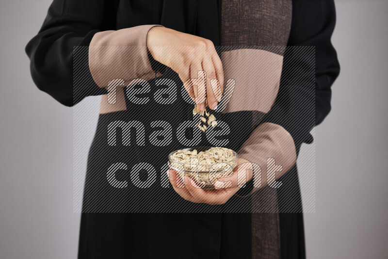 Woman in abaya holding different kinds of legumes in different positions