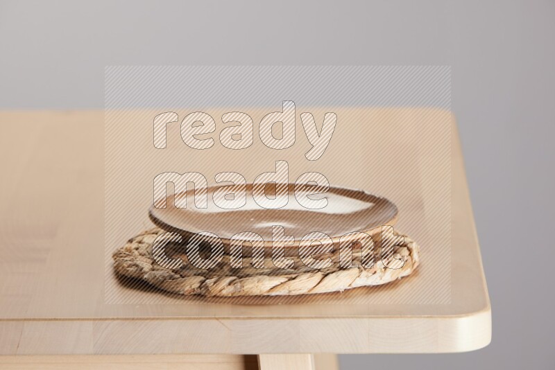 multi-colored pottery Plate placed on a small light colored straw placemat on the edge of wooden table