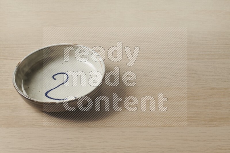 A multicolored pottery bowl on light wooden background