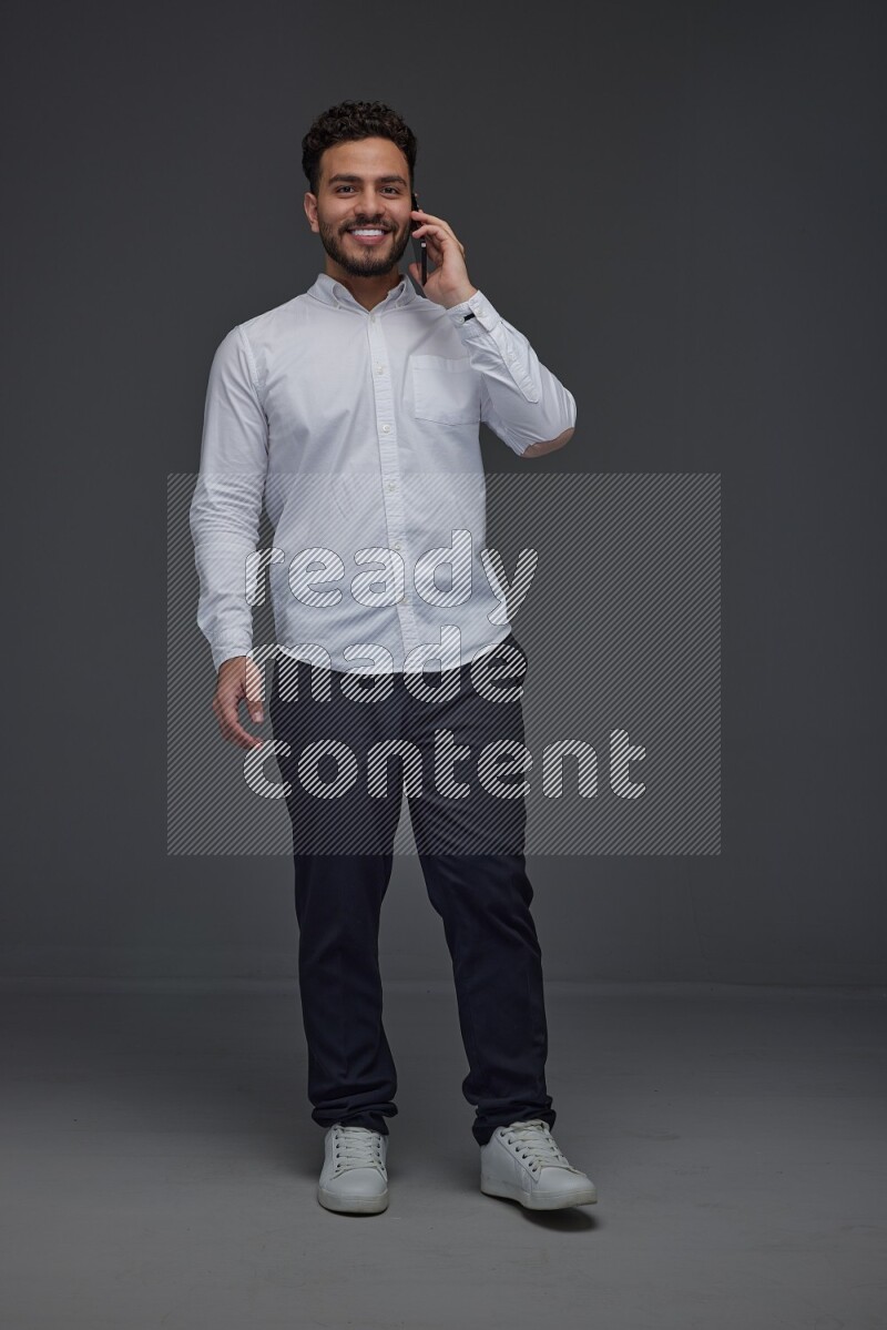A man wearing smart casual talking in the phone eye level on a gray background