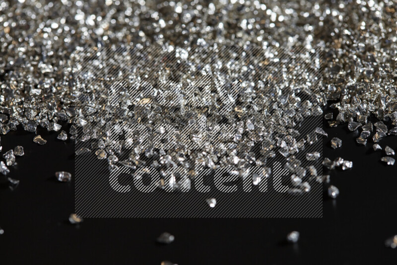 Silver shimmering fragments of glass scattered on a black background