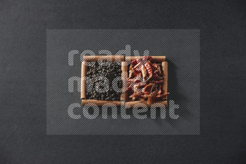 2 squares of cinnamon sticks full of chilis and black peppers on black flooring
