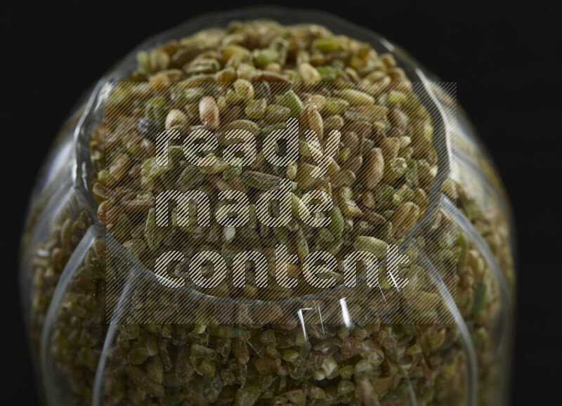 Freekeh in a glass jar on black background