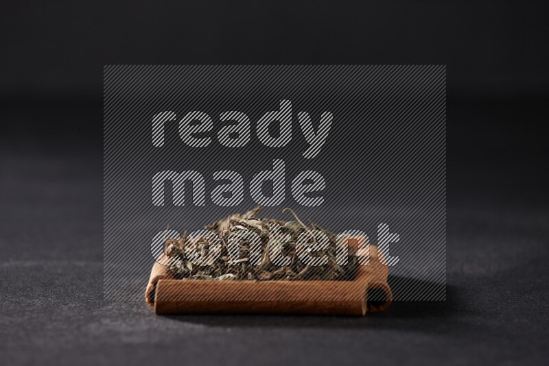 A single square of cinnamon sticks full of dried basil on black flooring