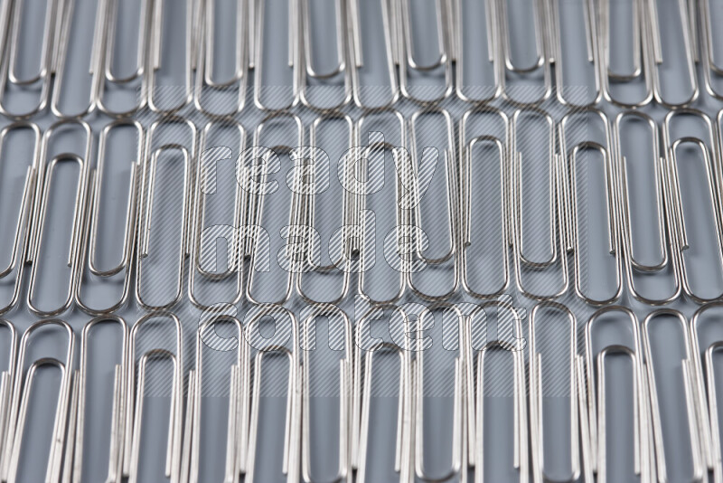 Silver paper clips isolated on a grey background