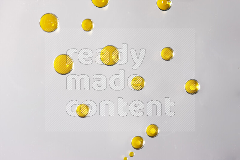 Close-ups of abstract yellow watercolor drops on oil Surface on white background