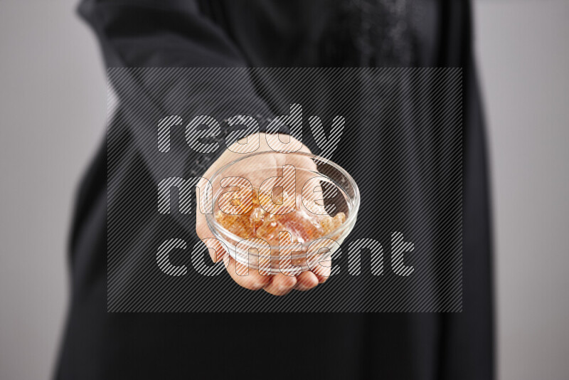 Woman in abaya holding different kinds of spices in different positions