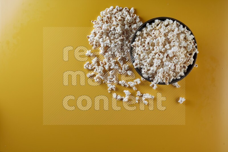 A copper ceramic bowl full of popcorn with popcorn beside it on a yellow background in different angles