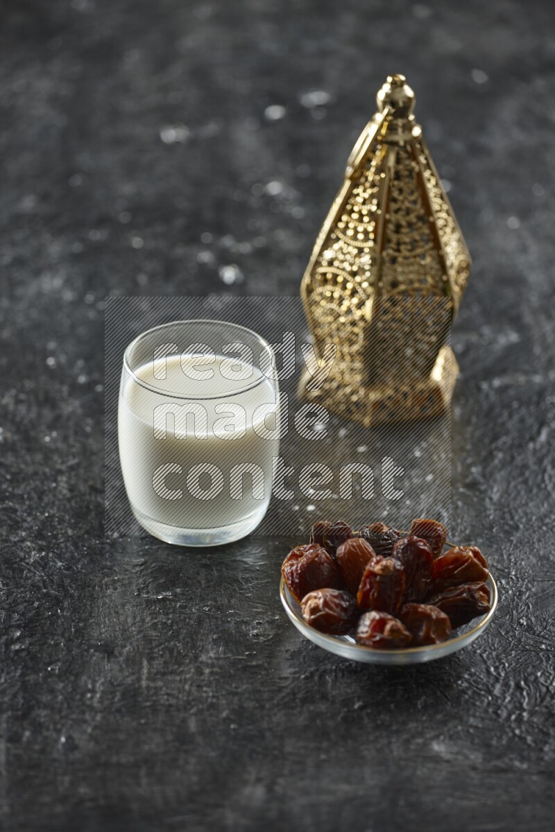 A golden lantern with different drinks, dates, nuts, prayer beads and quran on textured black background