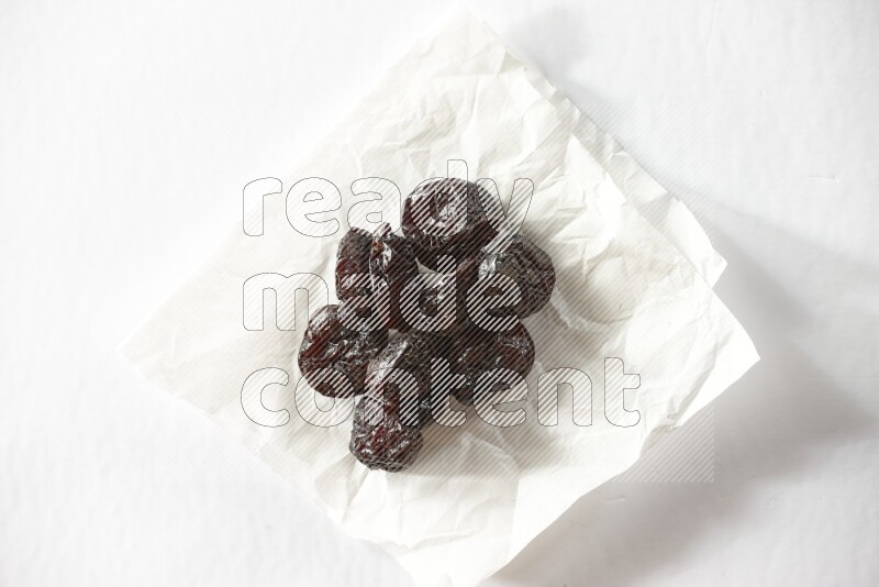 Dried plums on a crumpled piece of paper on a white background in different angles