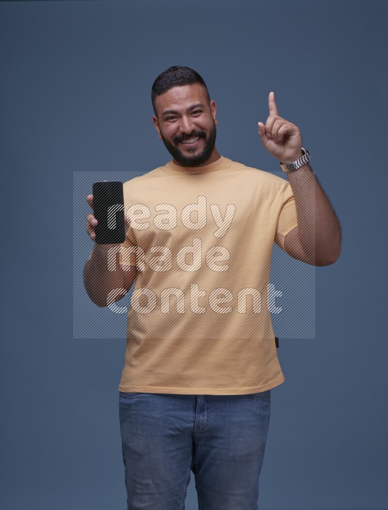 A man Playing Games on Smartphone on Blue Background wearing Orange T-shirt