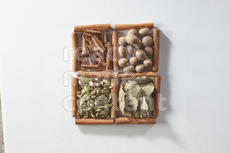 4 squares of cinnamon sticks full of nutmegs, bay laurel leaves, cardamom and cinnamon on white flooring