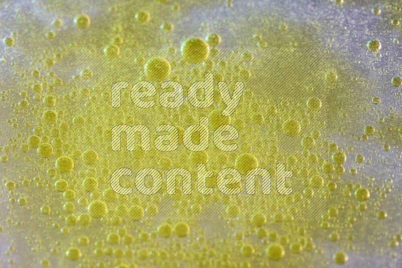 Close-ups of abstract yellow watercolor drops on oil Surface on white background