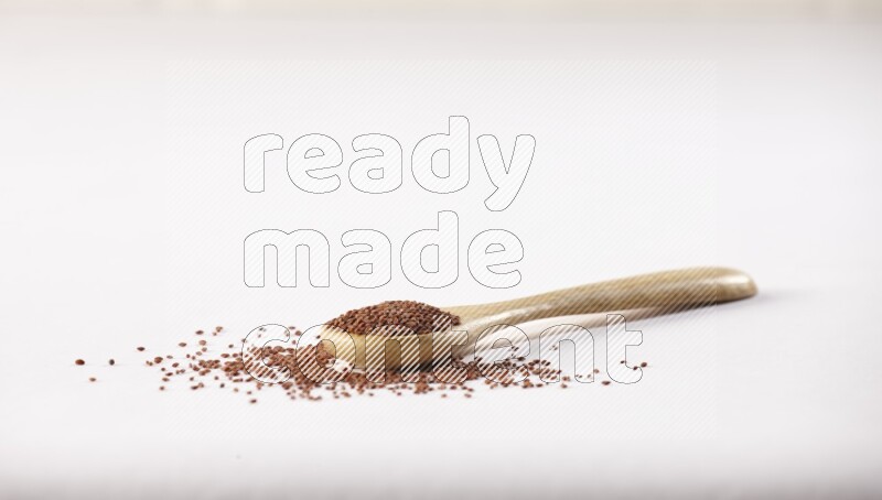 A wooden spoon full of garden cress seeds on a white flooring
