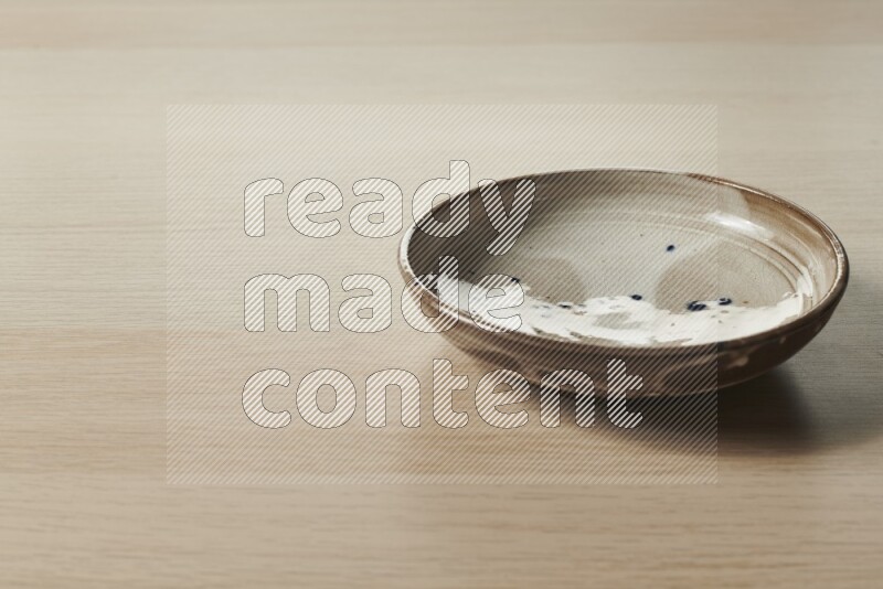 A multicolored pottery plate on light wooden background