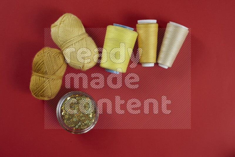 A yellow collection of sewing and tailoring tools arranged on a red background