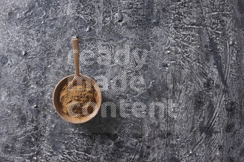 Wooden bowl full of cinnamon powder with a wooden spoon on a textured black background in different angles
