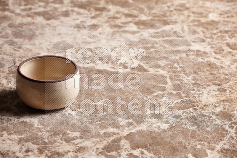 A beige pottery oven bowl on beige marble background