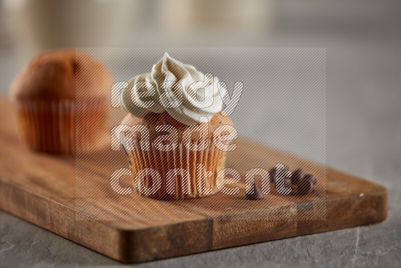 Vanilla cupcake topped with cream on a wooden board