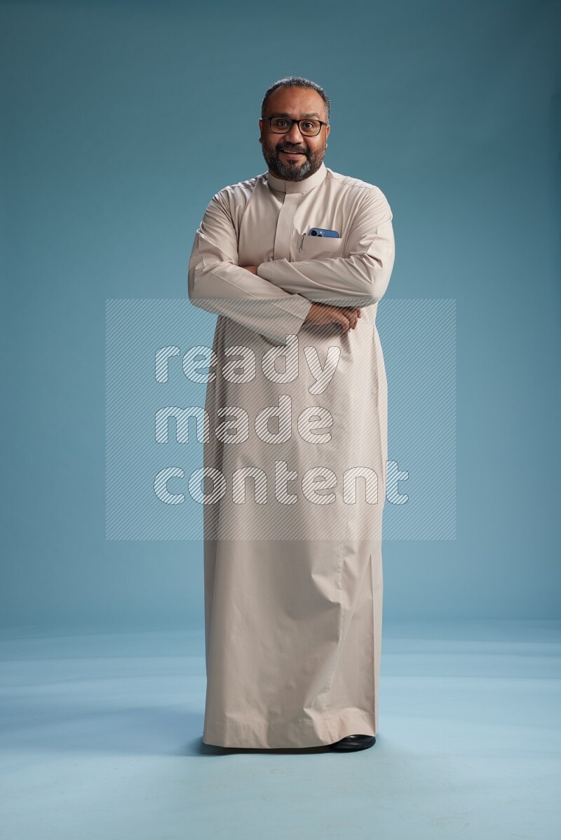 Saudi Man without shimag Standing Interacting with the camera on blue background