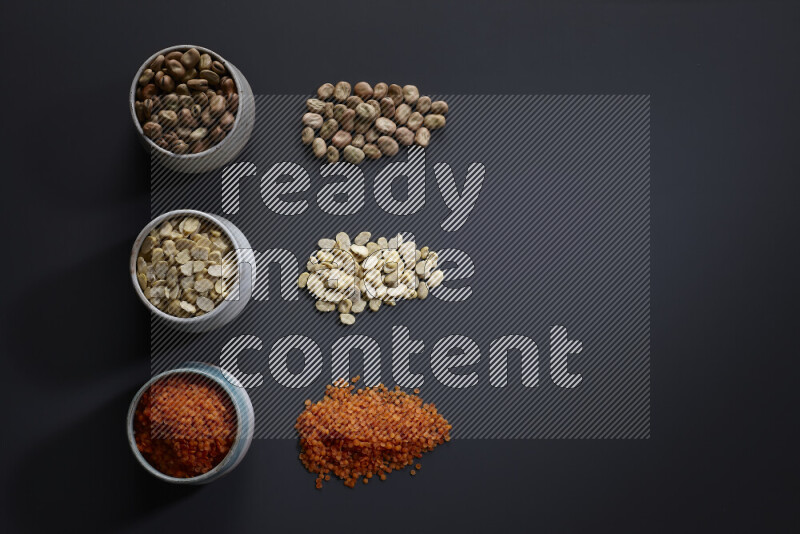 Legumes in pottery bowls on grey background